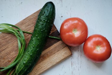 Salatalık ve domatesler beyaz bir masada.
