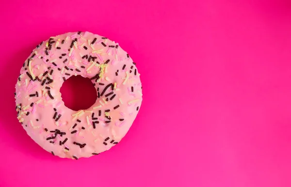 pink donut on a bright pink background cheers up