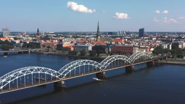 RIGA, Letonia - MAYO 2019: Vídeo aéreo con vista panorámica del puente ferroviario sobre un río y el centro de la ciudad de Riga . — Vídeo de stock