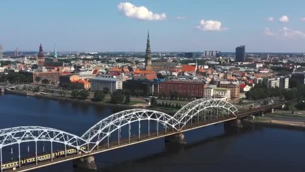 RIGA, LETTONIE - MAI 2019 : Vidéo aérienne avec vue panoramique sur le pont ferroviaire traversant une rivière et le centre-ville de Riga . — Video