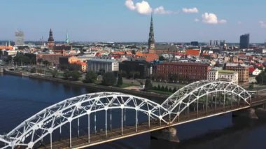 Riga, Letonya - Mayıs 2019: Nehir ve Riga şehir merkezi arasındaki demiryolu köprüsünün panorama manzaralı klibi.