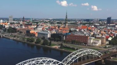 Riga, Letonya - Mayıs 2019: Riga şehir merkezi ve nehir boyunca uzanan demiryolu köprüsünün panorama manzaralı havacılık videosu.