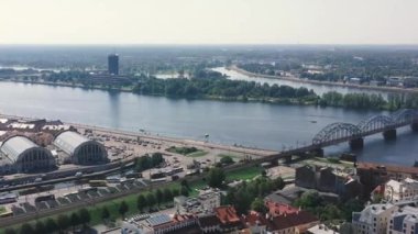 Riga, Letonya - Mayıs 2019: Daugava Nehri 'ni geçen merkez pazar ve demiryolu köprüsünün hava aracı görüntüsü.