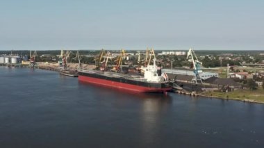 Ventspils, Letonya - Temmuz 2019: Ventspils limanındaki büyük kuru kargo gemisi ve gemi vinçlerinin hava aracı görüntüsü.