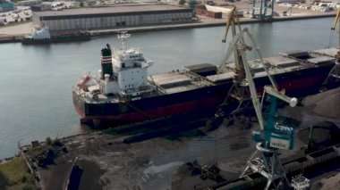 Ventspils, Letonya - Temmuz 2019: Ventspils limanındaki kargo gemisine kargo yükleyen iskele vinç görüntüsü.