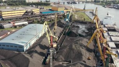 Ventspils, Letonya - Temmuz 2019: Kargoyu kuru kargo gemisi ve demiryolu vagonuna yükleyen iskele vinç görüntüsü.