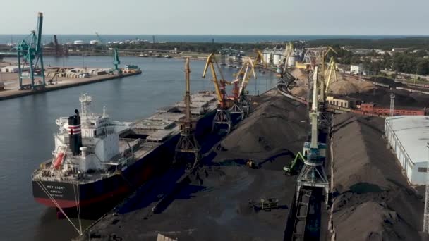 Ventspils, Letland - juli 2019: Luchtfoto van de havenkraan die vracht in het droge vrachtschip laadt en zicht op de haven. — Stockvideo