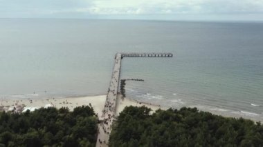 PALANGA, LITHUANIA - JULY, 2019: Aerial panorama view of people walking on the bridge of Palanga, sand beach and sea.