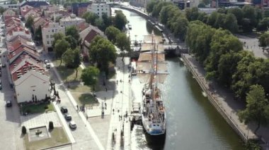 KLAIPEDA, LITHUANIA - JULY, 2019: Aerial flight view of the sailboat Meridianas in the river Dane in old city of Klaipeda.