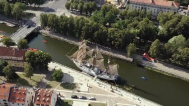 KLAIPEDA, LITHUANIA - JULY, 2019: Aerial flight view of the sailboat Meridianas in the river Dane in old city of Klaipeda.