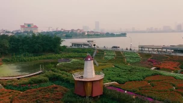 HANOI, VIETNAM - APRIL, 2020: Flygfoto över blomsterträdgården med dekorativa kvarn och utsikt över den västra sjön Hanoi. — Stockvideo