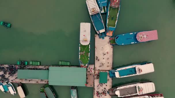 HALONG BAY, VIETNAM - APRIL, 2020: Bovenaanzicht vanuit de lucht op de pier met boten in de rotsachtige eilanden Halong Bay in Vietnam. — Stockvideo