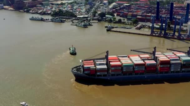 ГОЧИМИН, ВЬЕТНАМ - АПРЕЛЬ, 2020: Вид с воздуха на грузовое судно и буксир, направляющие его в порт Хохимин . — стоковое видео