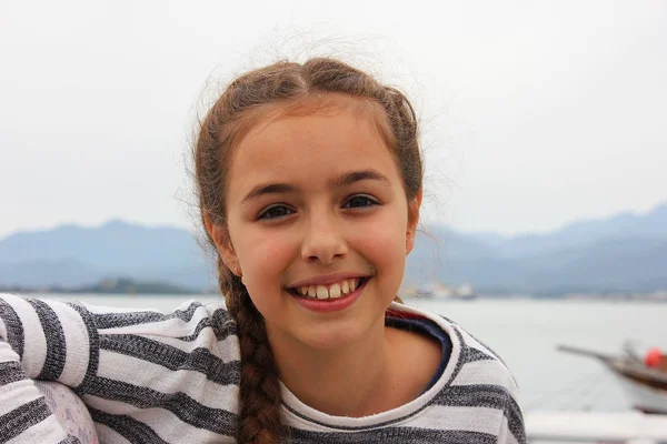 Usmívající se dívka sedící poblíž moře v přístavu Fethiye — Stock fotografie