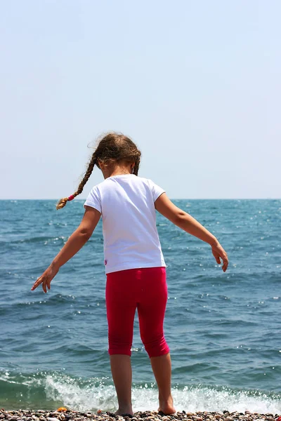 Liten flicka som leker på stranden i närheten av havet. — Stockfoto