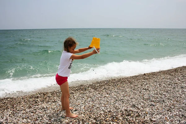 Liten flicka som leker på stranden i närheten av havet. — Stockfoto