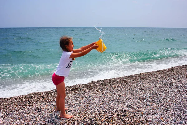 Liten flicka som leker på stranden i närheten av havet. — Stockfoto