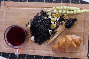 Siyah çay papatya, adaçayı ve kruvasan ahşap tepsi
