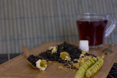 Bir tahta kaşık papatya ile siyah yaprak çay