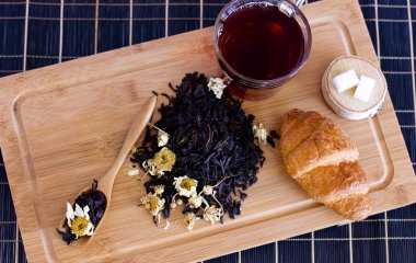 Siyah çay papatya, adaçayı ve kruvasan ahşap tepsi