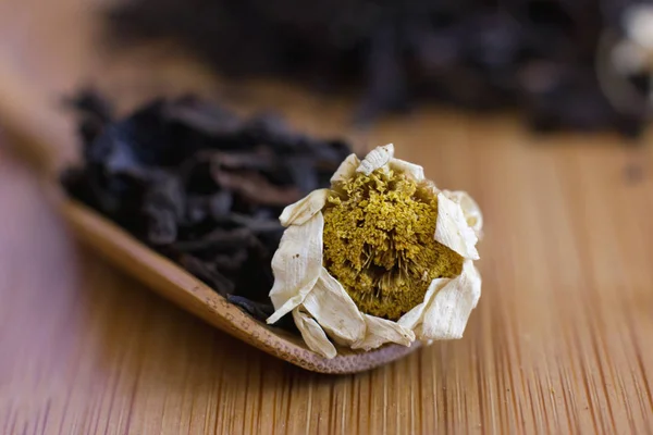 Chá de folha preta com camomila em uma colher de madeira — Fotografia de Stock