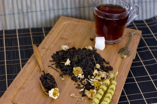 Chá de folha preta com camomila em uma colher de madeira — Fotografia de Stock