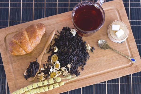 Siyah çay papatya, adaçayı ve kruvasan ahşap tepsi