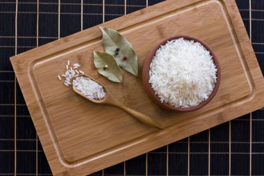 Beyaz pirinç bir kil kase ve bir tahta kaşık. Defne yaprağı ve 