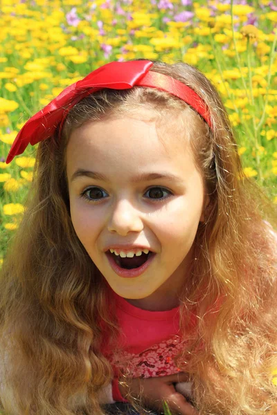 Улыбающаяся маленькая симпатичная девочка в жёлтых цветах. Красные носовые узлы — стоковое фото