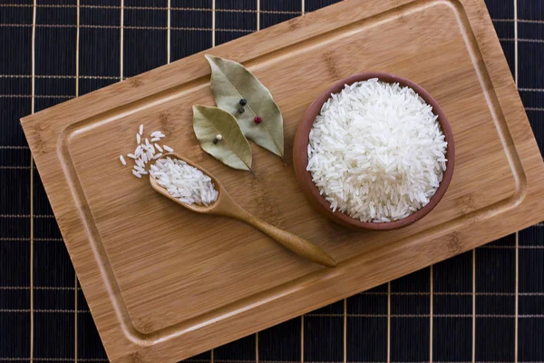 Beyaz pirinç bir kil kase ve bir tahta kaşık. Defne yaprağı ve 