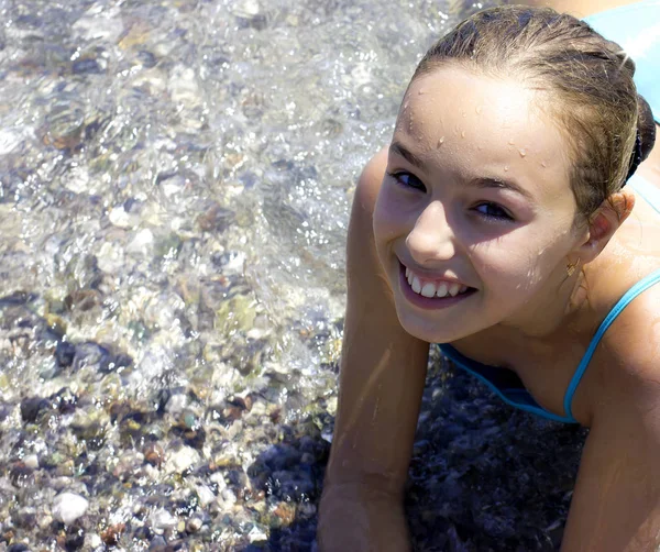 年轻漂亮的小女孩微笑着在蓝色泳装在海面上 bea — 图库照片