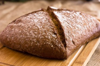 Çuval bezi üzerinde ahşap bir tepside karanlık çavdar ekmeği