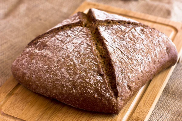 Çuval bezi üzerinde ahşap bir tepside karanlık çavdar ekmeği