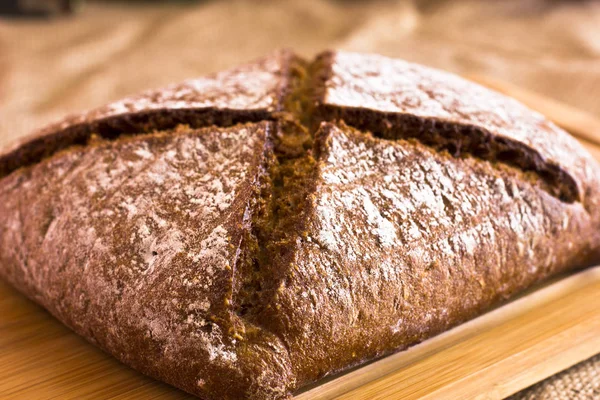 Çuval bezi üzerinde ahşap bir tepside karanlık çavdar ekmeği