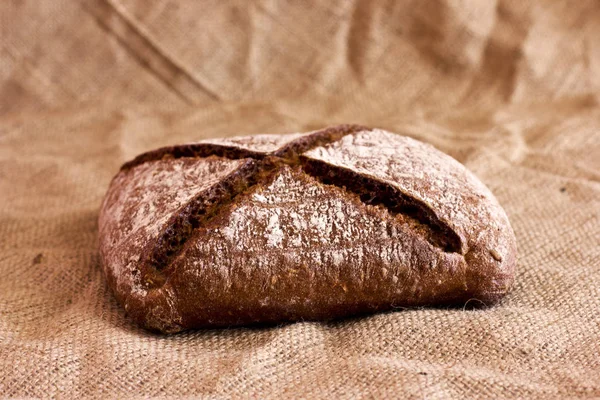 Pão escuro de centeio em uma travessa de madeira na serapilheira — Fotografia de Stock
