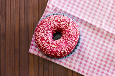 Kahverengi ahşap arka plan üzerinde parlak pembe çörek. Pembe ch ile