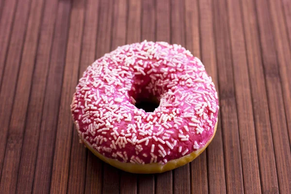 Leuchtend rosa Donut auf braunem Holzgrund — Stockfoto