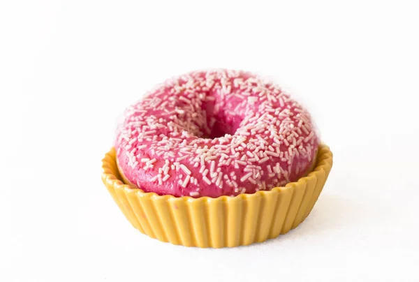 Leuchtend rosa Donut auf weißem Hintergrund in gelber Keramik — Stockfoto