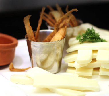 Kaşar peyniri, beyaz bir tabağa şeritler halinde kesin. Mısır cipsi bir