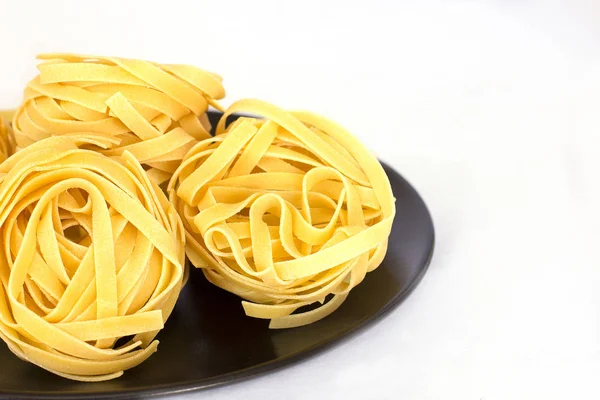 블랙 세라믹 접시에 생 쌀된 tagliatelle입니다. 절연 — 스톡 사진