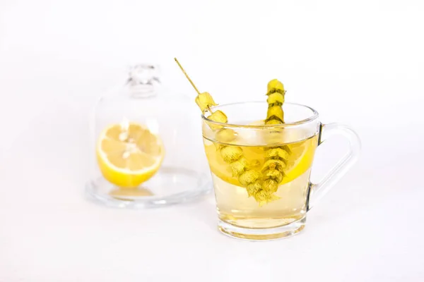 Hot tea with sage and lemon in a glass mug.