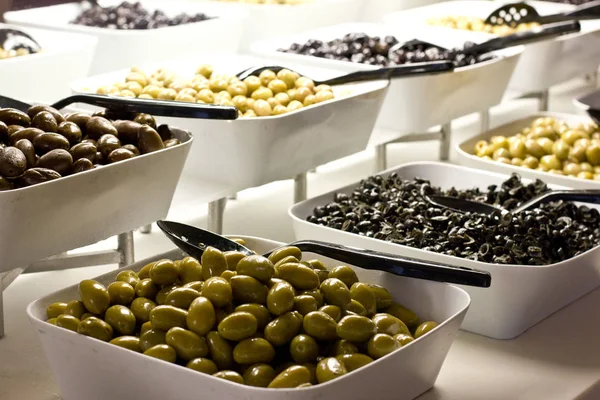 Выбор черных и зеленых оливок в белых чашах — стоковое фото