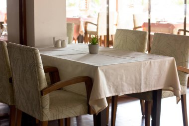 Bir tablo ile ar tarafından çevrili bir restoranda bej bir masa örtüsü