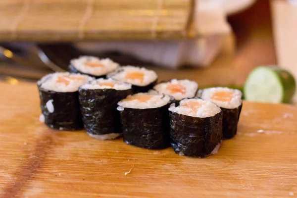 Preparação de rolos japoneses de salmão. Rolos em uma boa de madeira — Fotografia de Stock