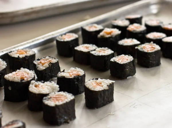Preparação de rolos japoneses de salmão. Rolos em uma bandeja metálica — Fotografia de Stock