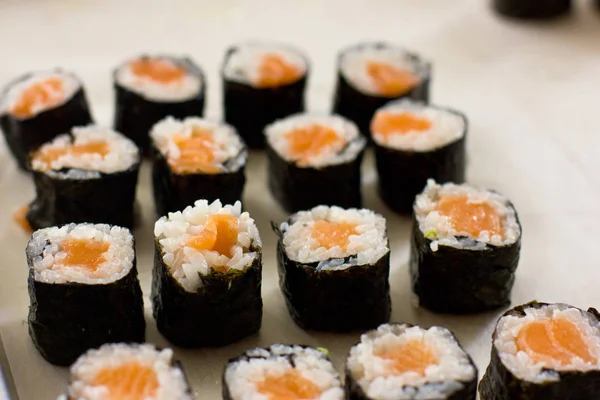 Preparação de rolos japoneses de salmão. Rolos em uma bandeja metálica — Fotografia de Stock