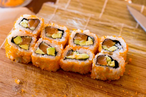 Japanse sushi en rollen met zalm, avocado, komkommer en flyi — Stockfoto