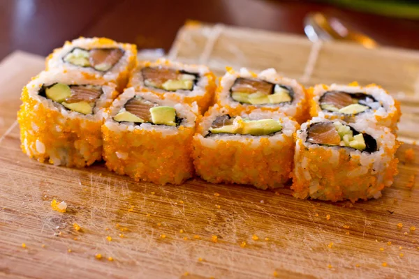 Japanse sushi en rollen met zalm, avocado, komkommer en flyi — Stockfoto