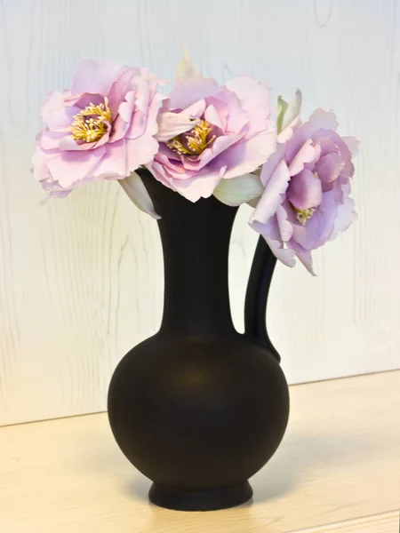 Rosa pioner i en svart vas. Konstgjorda sidenblommor i int — Stockfoto