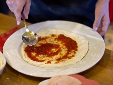 Aşçı pizza yapıyor. Hamur için domates sosu